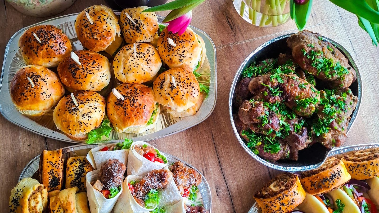 Catering uPICHcone z Grzędzic: mini burgery z czarnuszką, tortille z mięsem, kotleciki z natką pietruszki, paszteciki francuskie i sałatka z szynką dojrzewającą, obok wiosenne tulipany