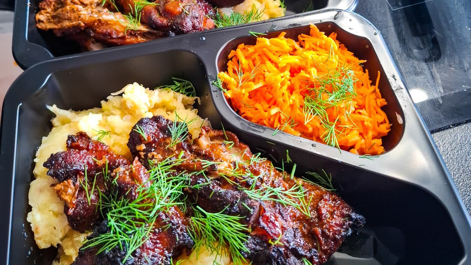 Pieczone żeberka w glazurze z puree ziemniaczanym i surówką z marchewki, pakowane w pudełka na wynos