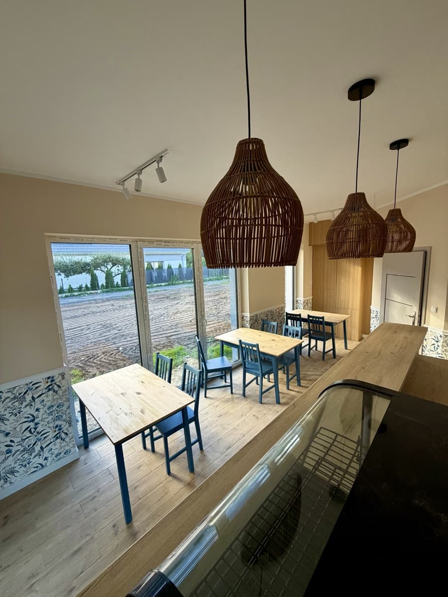 Wnętrze bistro uPICHcone w Zieleniewie (gmina Stargard) — sala z drewnianymi stołami, niebieskimi krzesłami i wiklinowymi lampami