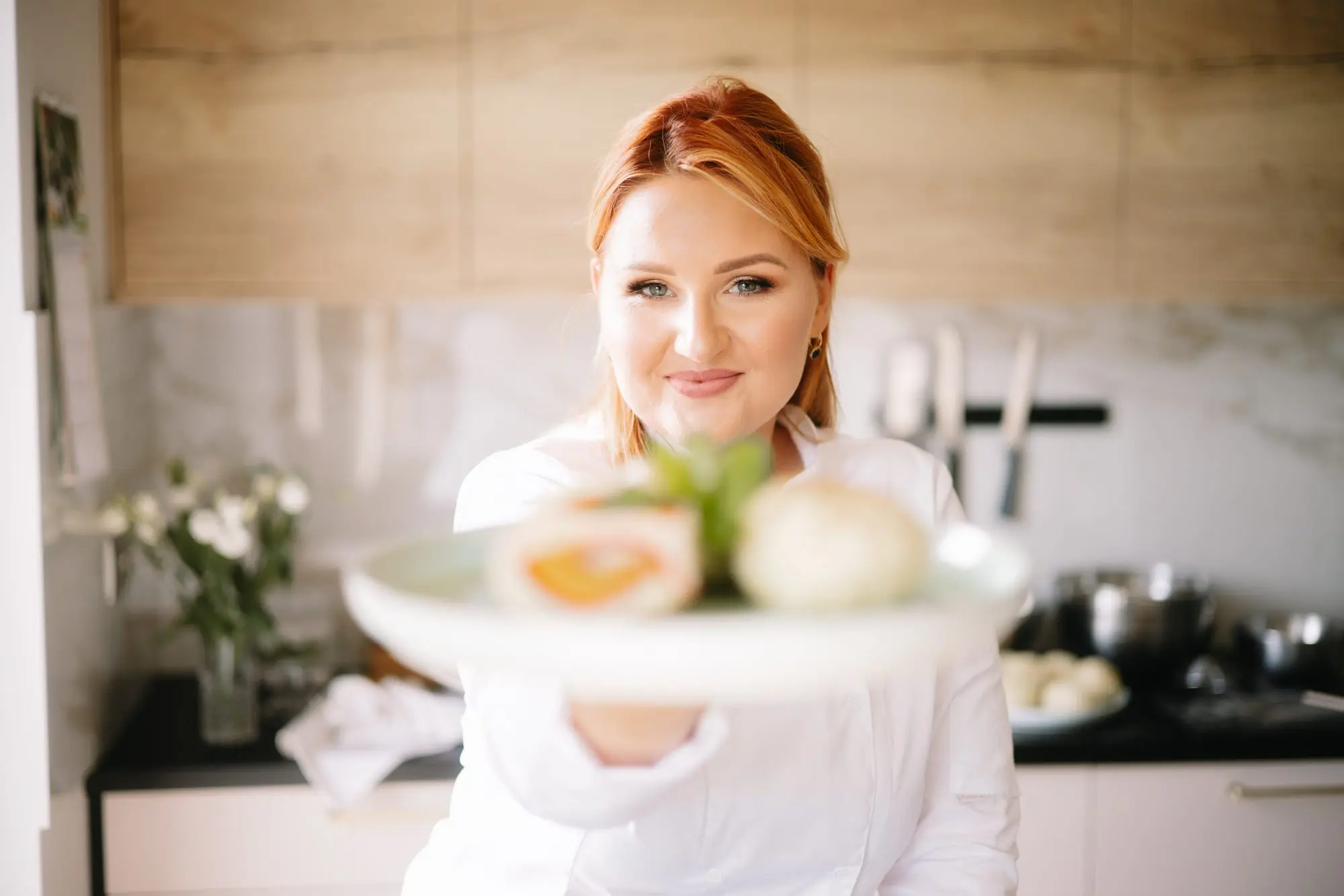 Daria, właścicielka bistro uPICHcone w Zieleniewie pod Stargardem, w białym kitlu kucharskim podaje talerz z przekąskami